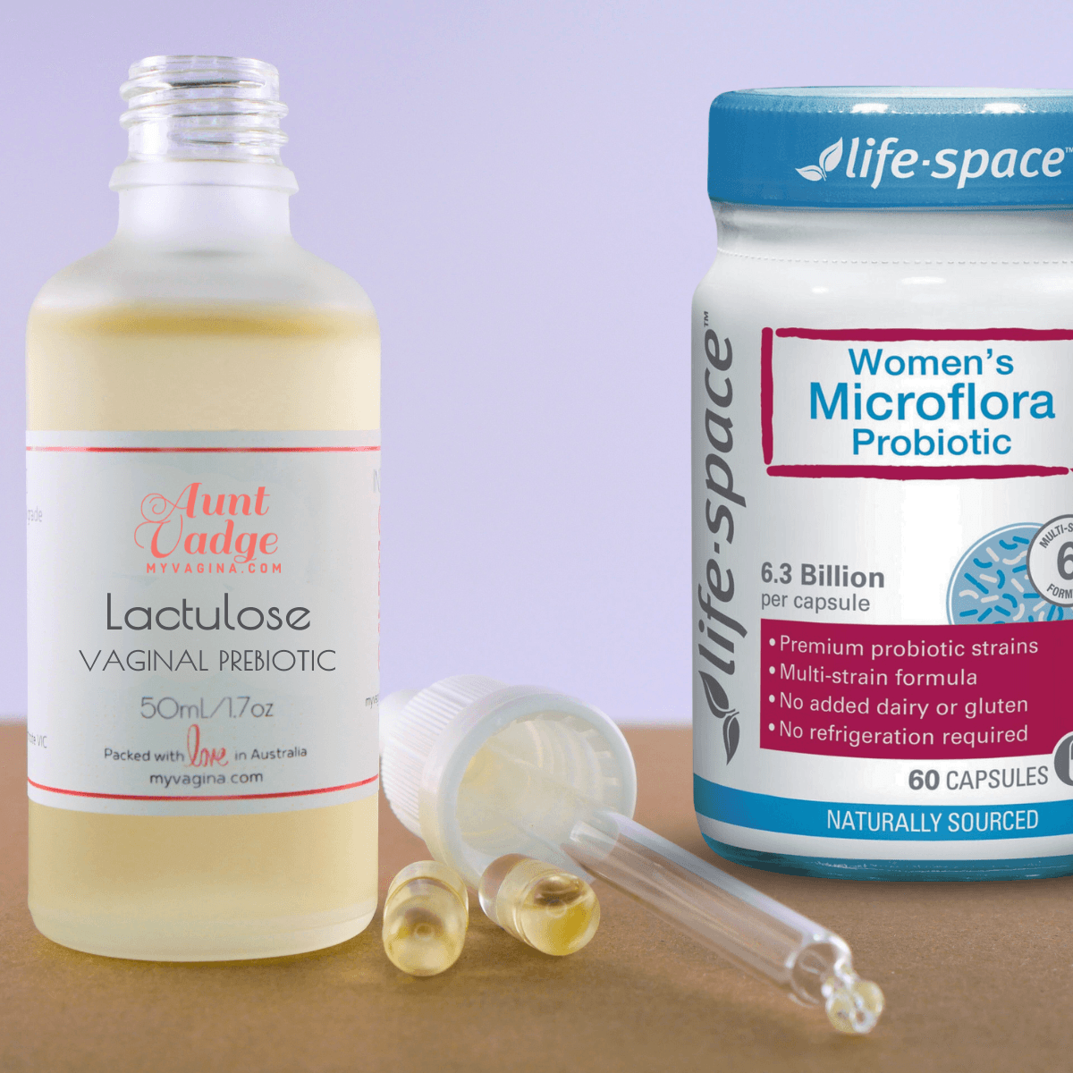 A bottle of lactulose, dropper cap off, sits with two full vegetable capsules and a jar of Life-Space Women's Microflora Probiotics.