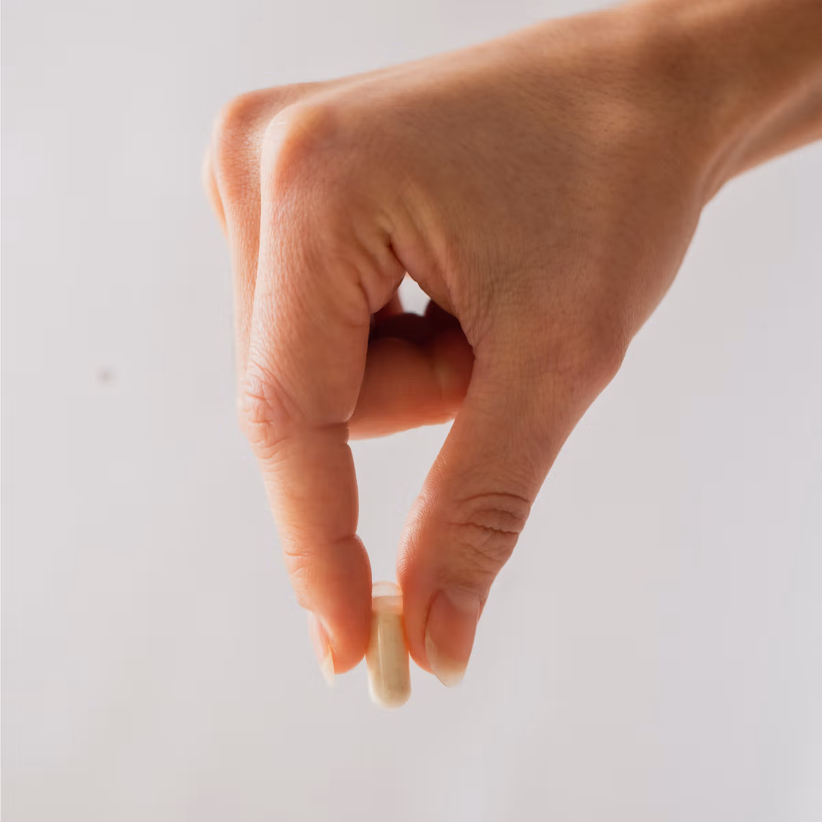 A hand holding a single V-Spot probiotic vaginal pessary