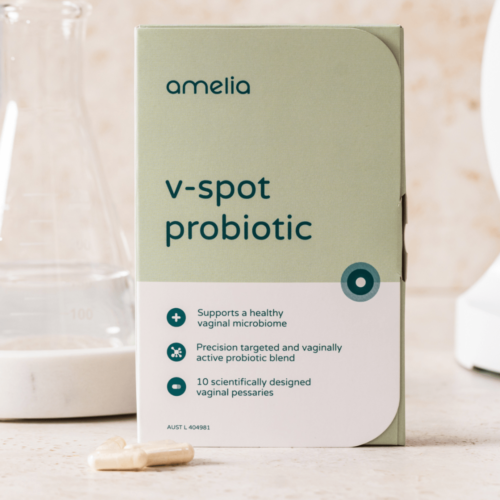 The pack of V-spot vaginal probiotics sit in front of a beaker and microscope.