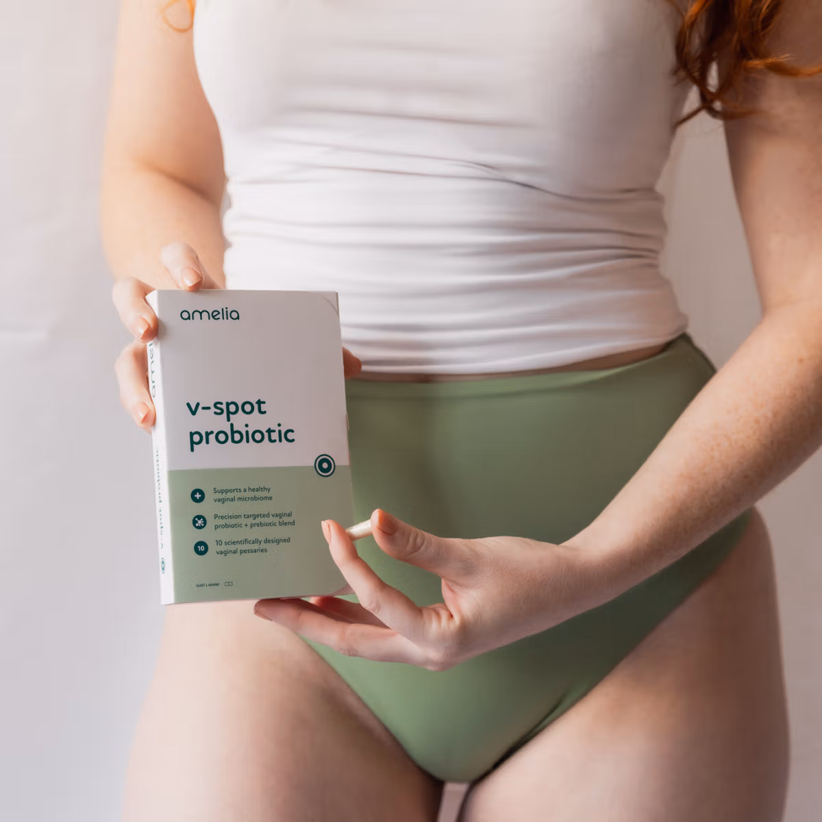 A woman holding the Amelia V-Spot Probiotic box at her hip