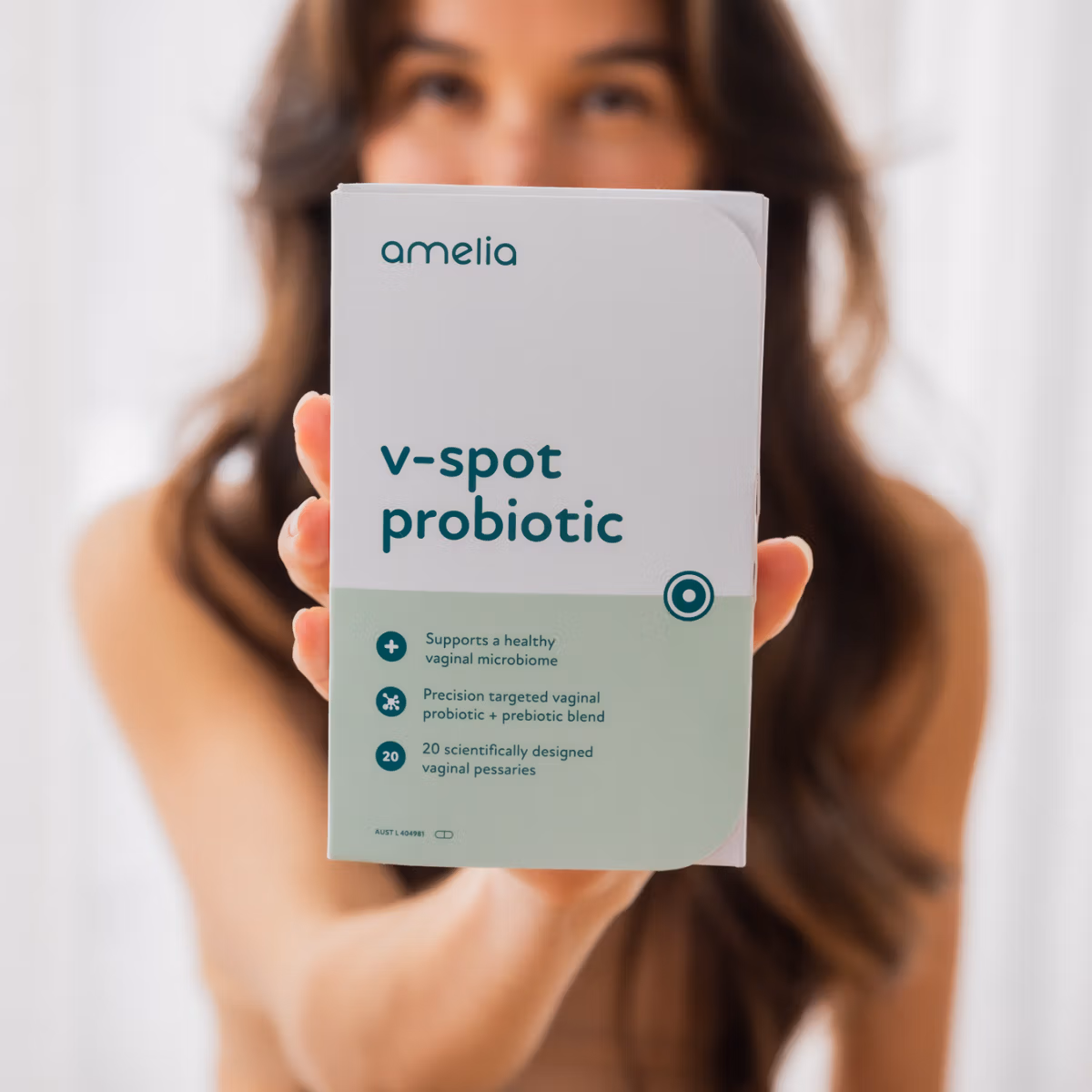 A woman holding up the Amelia V-Spot Probiotic box to the camera